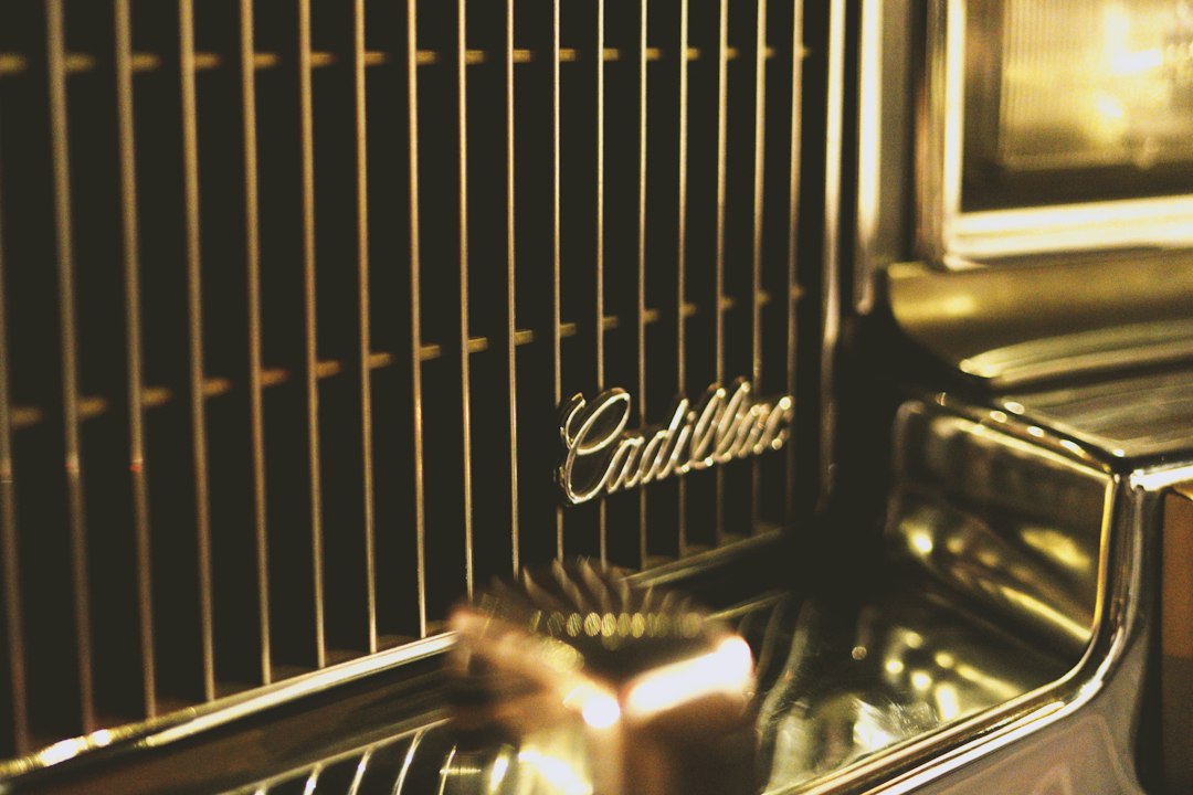 Close-up of the front grille and headlight of a classic Cadillac car, featuring the Cadillac emblem in cursive lettering—a true gem in the luxury market and among today’s most coveted collectibles.