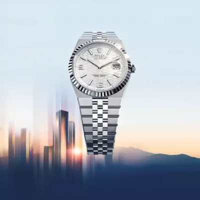 A luxury silver Rolex watch with a white dial and date display is showcased against a blurred city skyline and soft sunrise background.