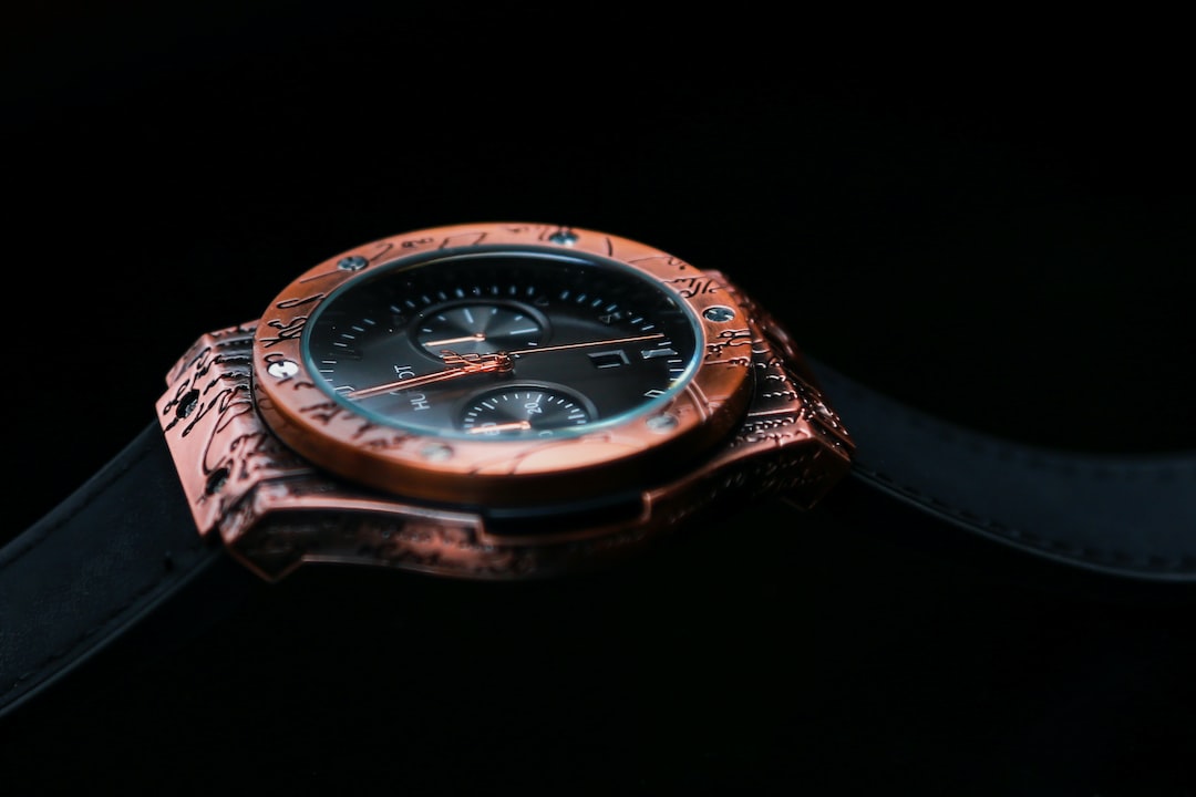 Close-up of a luxury wristwatch with a rose gold bezel, intricate engravings, and a black leather strap—an exquisite example of exclusive watchmaking against a dark background.