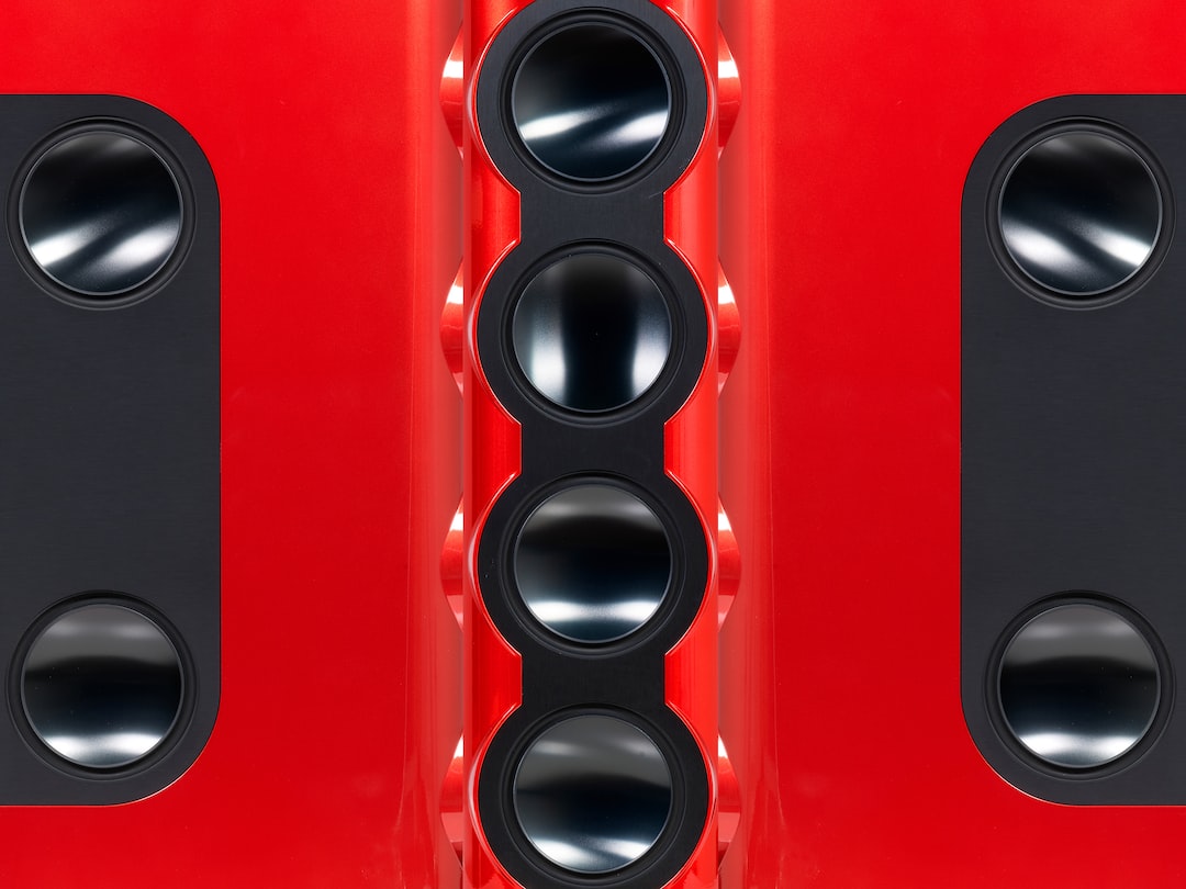 Close-up of a symmetrical red machine with black circular and oval components arranged in neat rows, reminiscent of Elite Audio Equipment design.