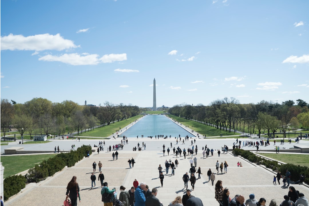 View from the Lincoln Memorial steps showing the Reflecting Pool, the Washington Monument, and crowds of people—including space tourists—on a clear day in Washington, D.C.