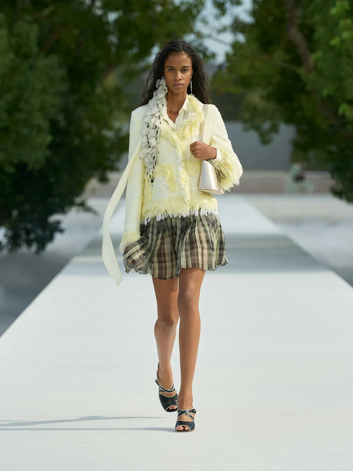 Dior Summer 2027 look 3: pale yellow fringed jacket with a ruffled scarf and a plaid mini skirt