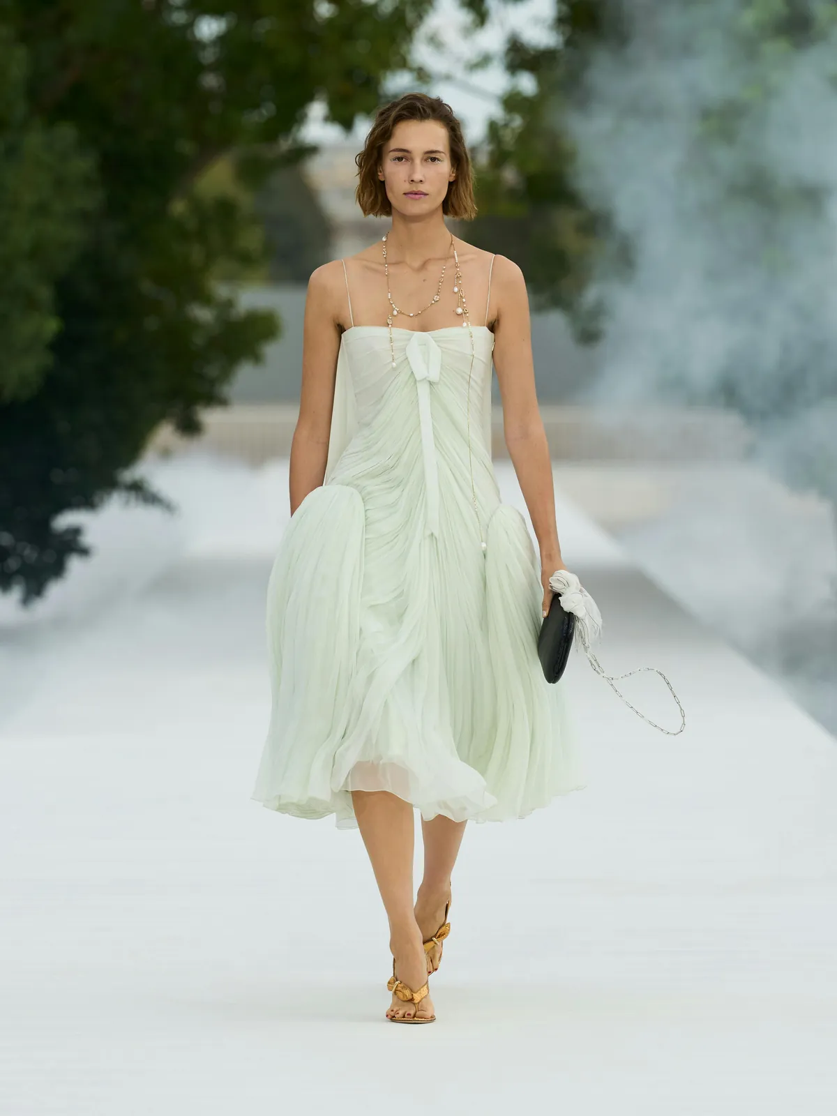Dior Summer 2027 look 47: pale green sheer pleated dress with long necklaces