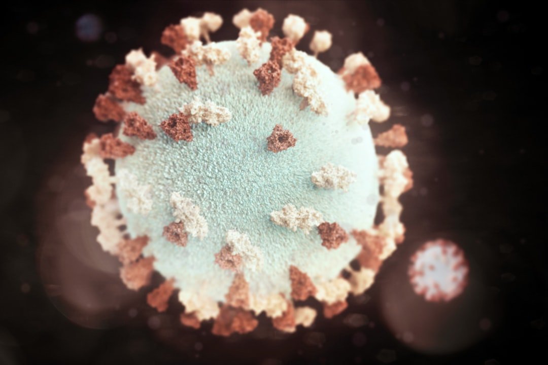A close-up digital illustration of a virus particle with spike proteins protruding from its surface, set against a dark blurred background—highlighting challenges faced by natural beauty and Bio-Kosmetik best brands in today’s world.