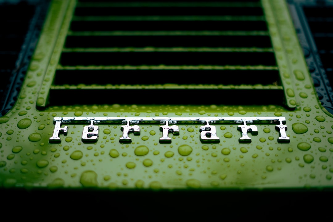 Close-up of a green Ferrari car with water droplets on the surface and the Ferrari logo in focus, capturing a sense of Italian glamour.