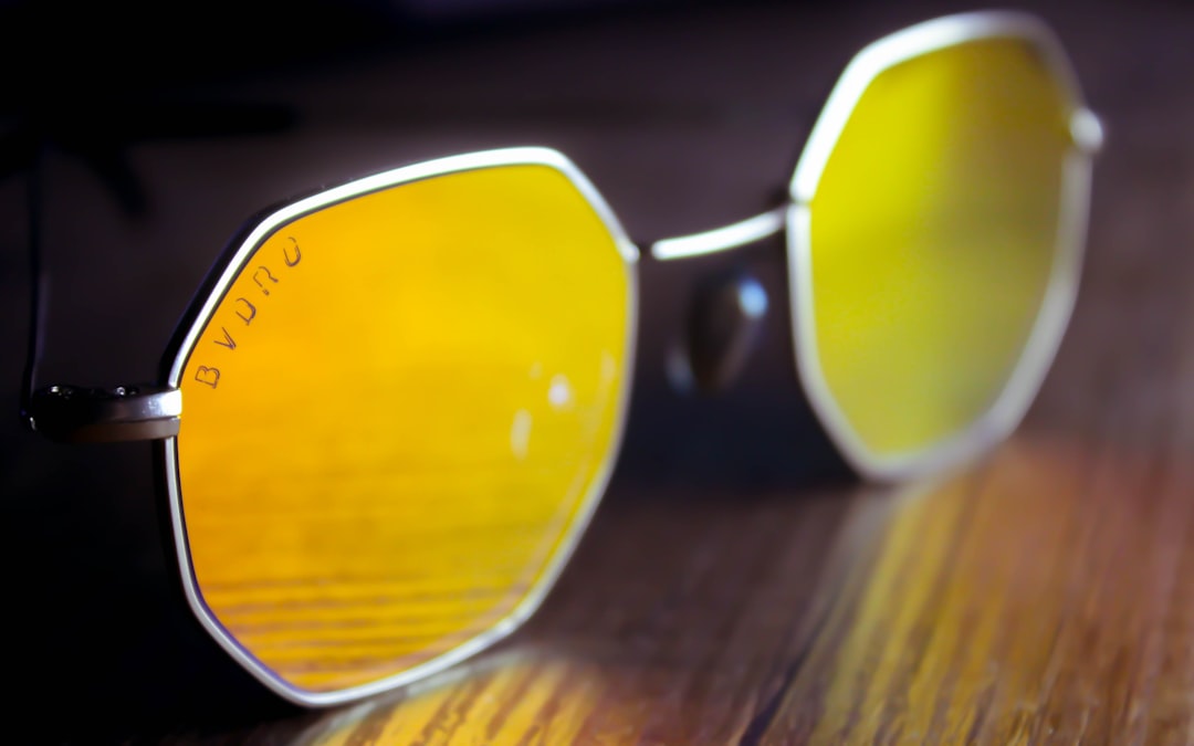 A pair of hexagonal sunglasses with yellow-tinted lenses and silver frames rests on a wooden surface, evoking the allure of exclusive access to famous landmarks.