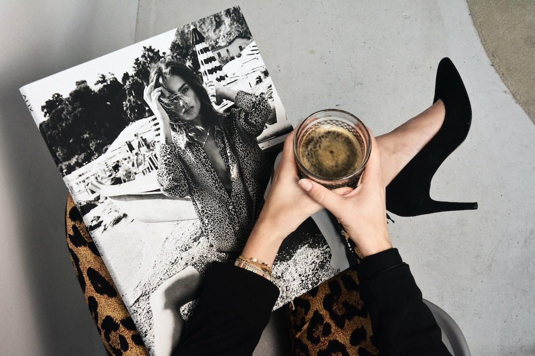 A person holding a glass of dark beverage sits with legs crossed, wearing leopard print pants and black heels, holding a black-and-white photo of a woman—an image that evokes the sophistication of exclusive wealth management.