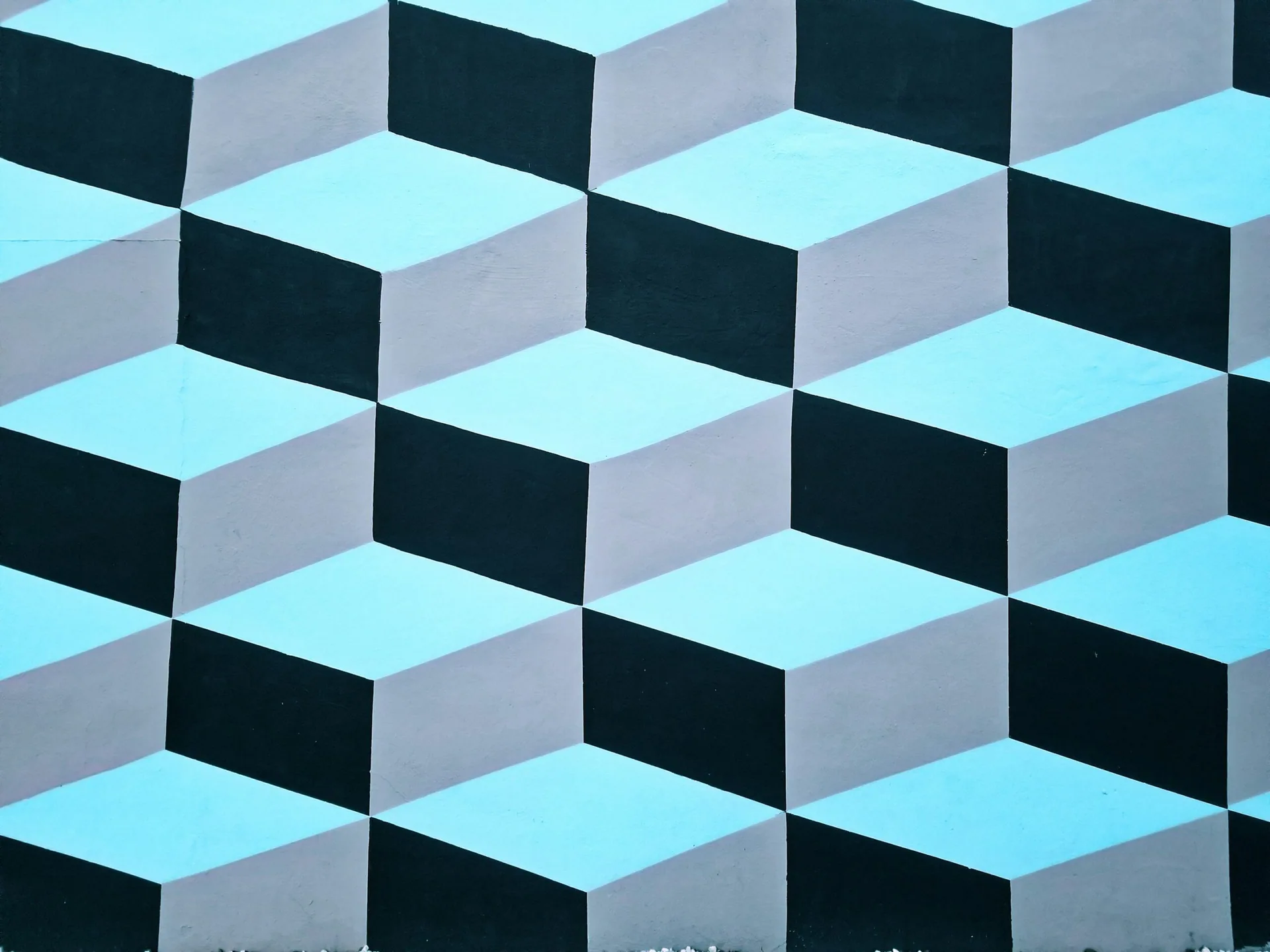 A wall painted with an optical illusion pattern of blue, black, and gray cubes, arranged in a repeating geometric design—perfect for stylish spaces or luxury golf trips.