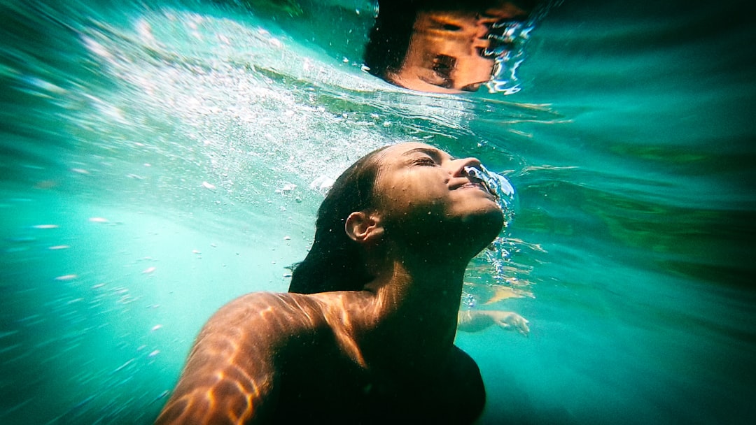 A person swims underwater near the surface, sunlight and reflections shimmering in the clear blue water—capturing the essence of Mediterranean sailing adventures.