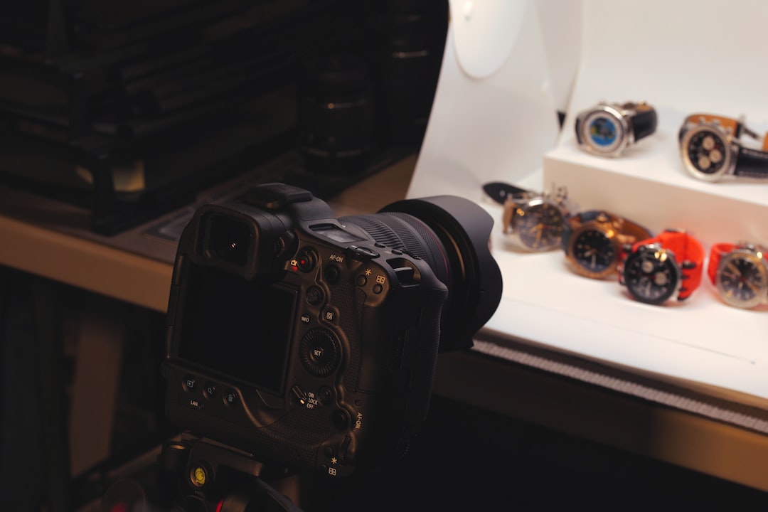 A digital camera on a tripod is positioned to photograph several Breguet wristwatches, showcasing the elegance of their classic collections in a lightbox setup.