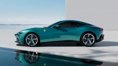 A luxury teal Ferrari sports car is parked beside a pool, its image reflecting in the water against a minimalist outdoor backdrop.