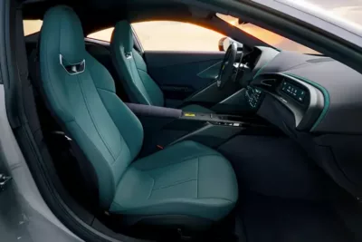 Interior view of a luxury modern car featuring two teal leather front seats, a sleek center console, dashboard, and steering wheel adorned with ambient lighting.