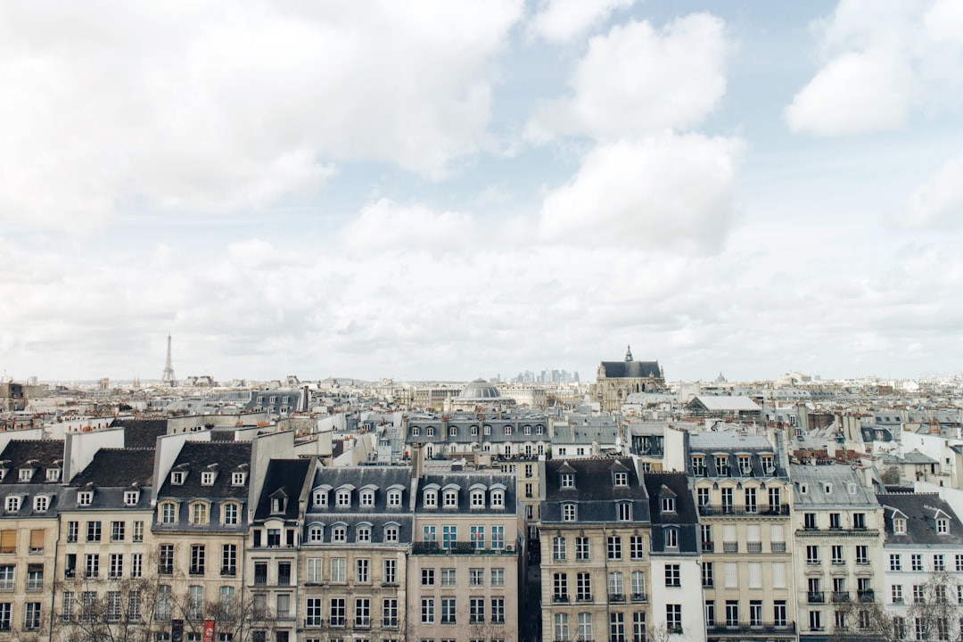 Wide view of Paris rooftops under a partly cloudy sky, with historic buildings and the iconic City of Love skyline—home to many luxurious boutique hotels nestled among the elegant streets.