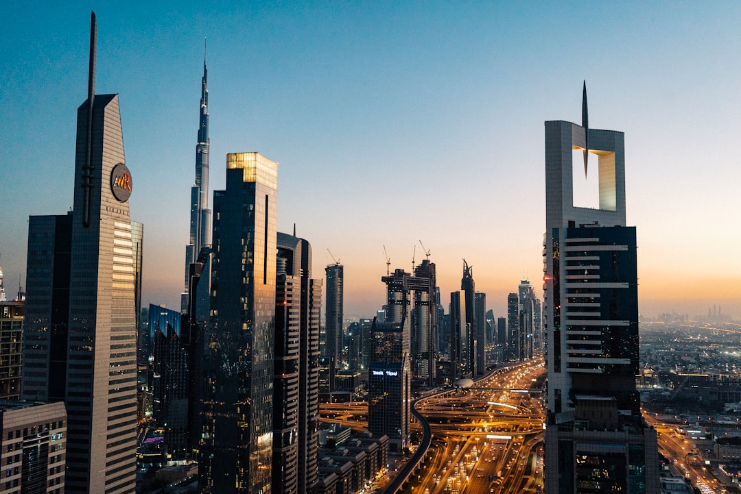 A cityscape at dusk shows modern skyscrapers and highways in Dubai, with the Burj Khalifa visible among the buildings under a clear sky, capturing the city's vibrant energy and world-class shopping experience.