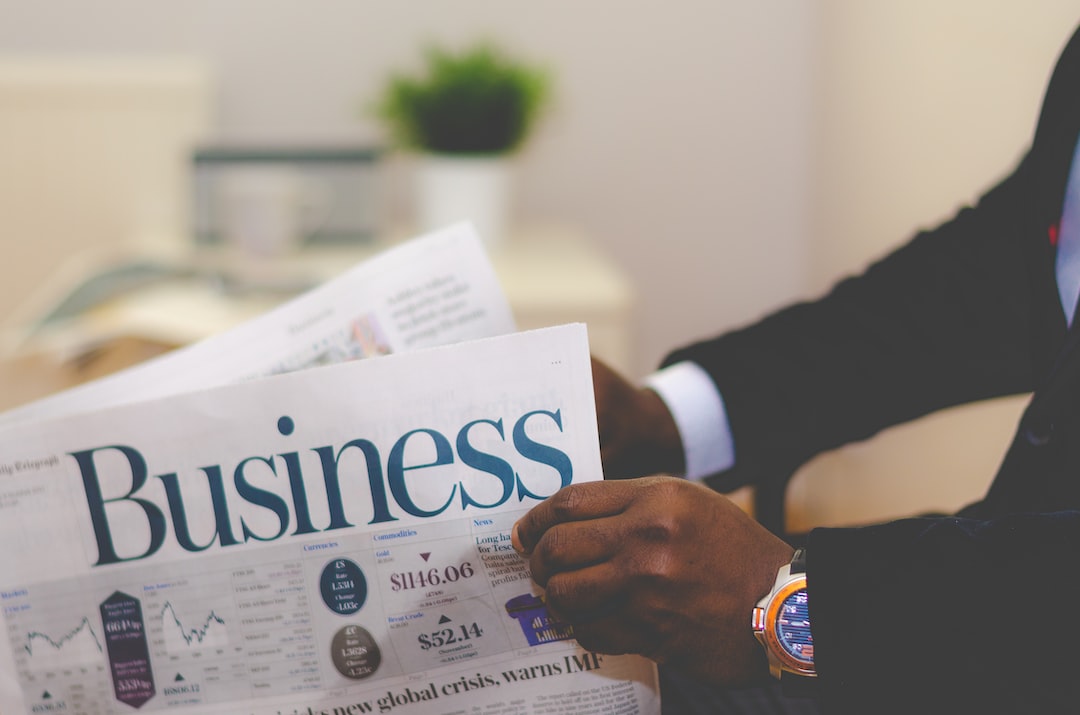 A person in a suit reads a newspaper with the headline "Business," seeking financial insights; a green potted plant is in the blurred background.