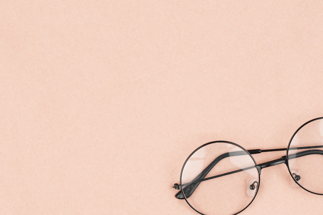 Round eyeglasses with black frames positioned on a light peach background in the lower right corner, capturing the timeless impact and sophistication seen in Karl Lagerfeld’s iconic fashion houses.