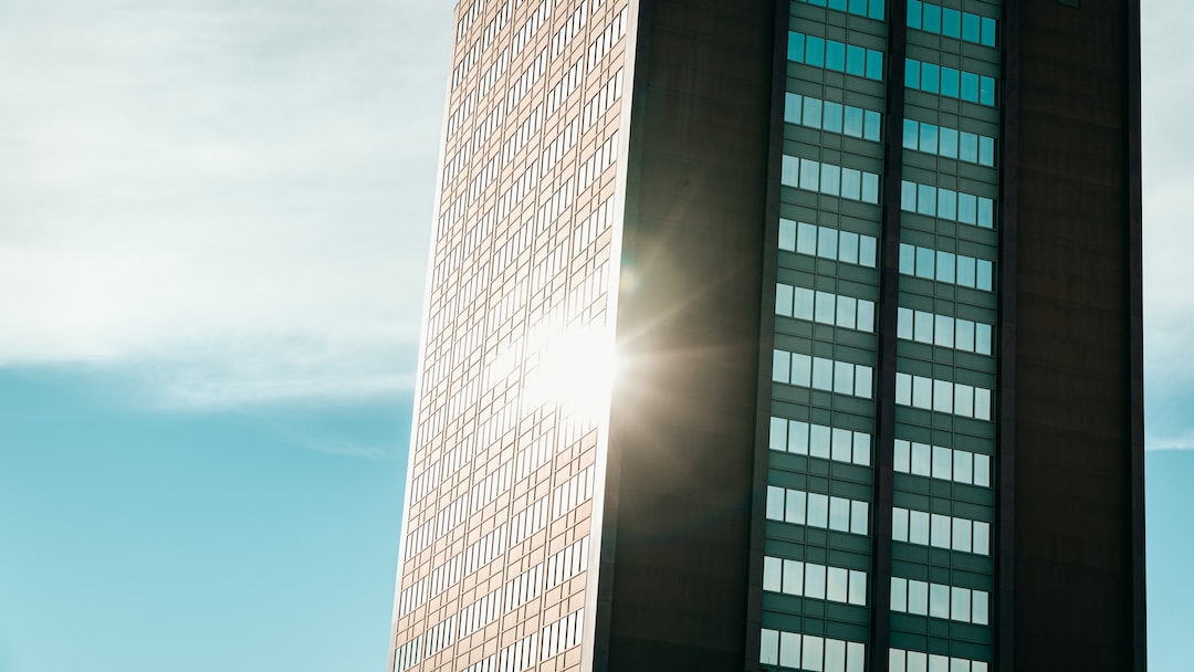 Sunlight reflects off the glass windows of a luxury Toronto high-rise office building against a clear blue sky.