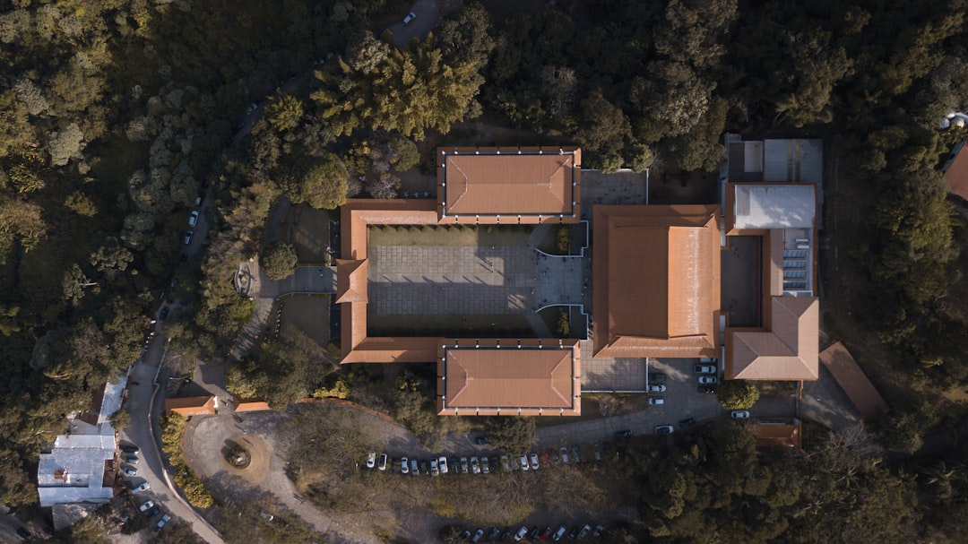 Aerial view of a large rectangular building with a central courtyard, nestled among trees and parked cars along nearby roads—a best-kept secret ideal for luxury travel enthusiasts seeking hidden gems.