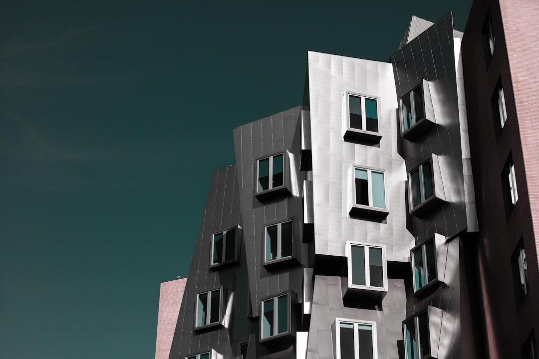 A modern building with irregular, angular metal panels and multiple windows stands against a dark sky, evoking the allure of luxury travel and the promise of a private chef’s exclusive culinary adventure within.