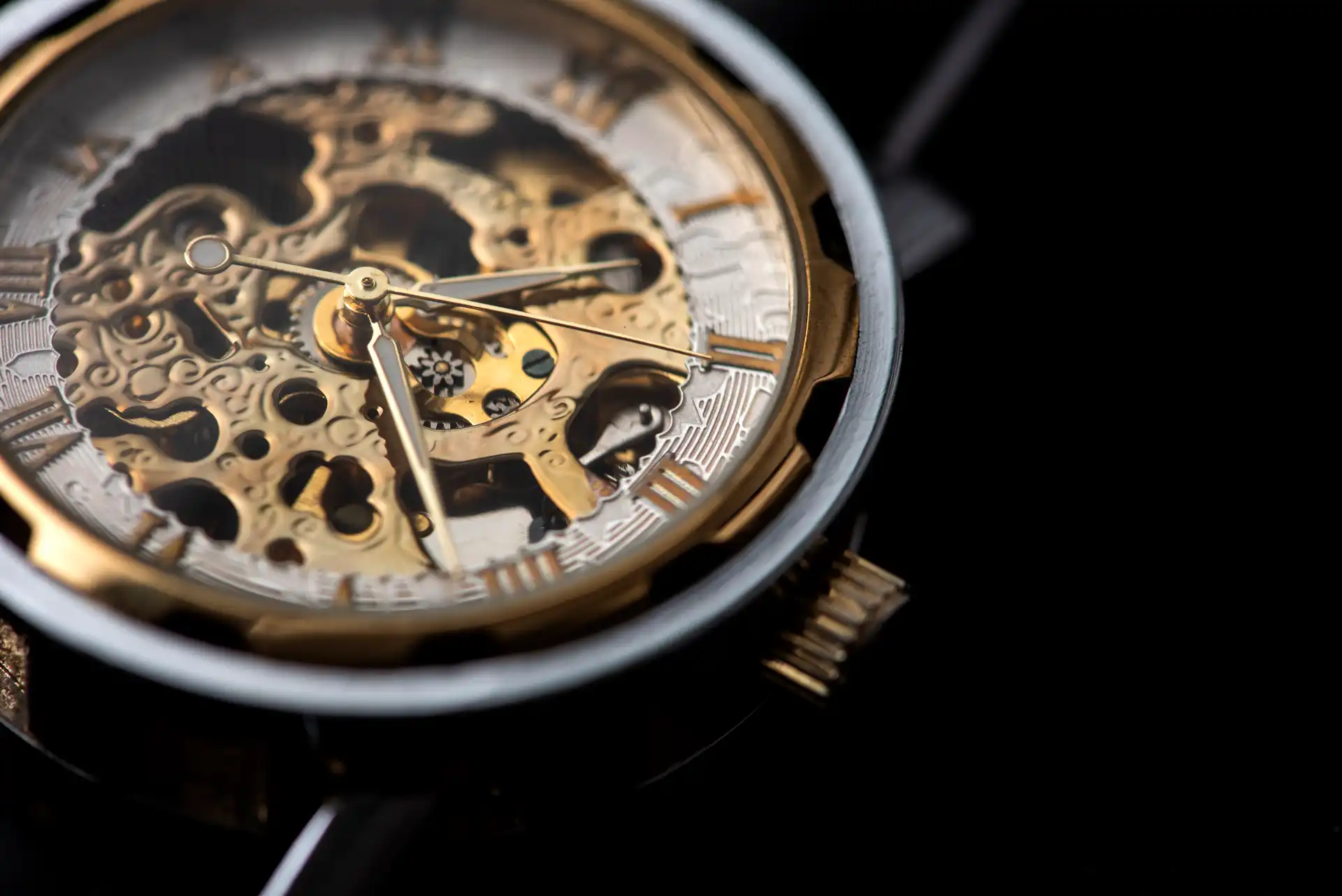 Close-up of a luxury skeleton watch with visible gold gears and Roman numeral hour markers, set against a black background.