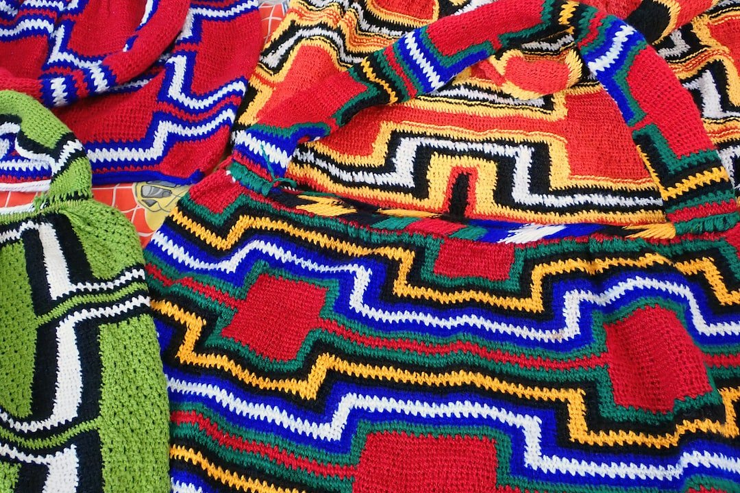 Close-up of colorful woven bags with geometric patterns in red, yellow, green, black, blue, and white, reminiscent of iconic Missoni Italian knitwear.