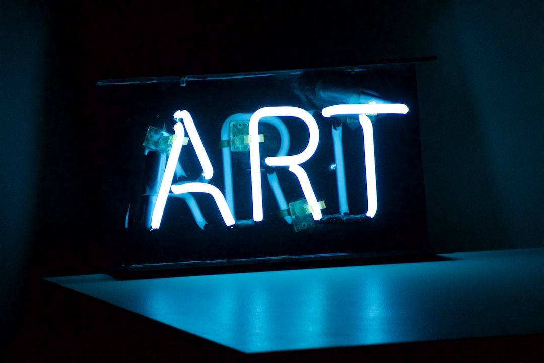 A blue neon sign spelling the word "ART" is illuminated in a dark room, reminiscent of displays seen at prestigious Art Auctions of the Year, resting on a flat surface.