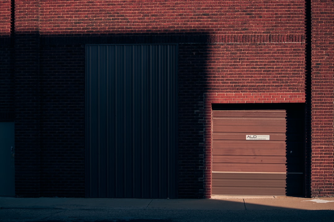 A red brick building with a large dark metal door and a smaller brown garage door with a sign, partially lit by sunlight and casting strong shadows—ideal for private tours of lesser-known sites near world-famous landmarks.