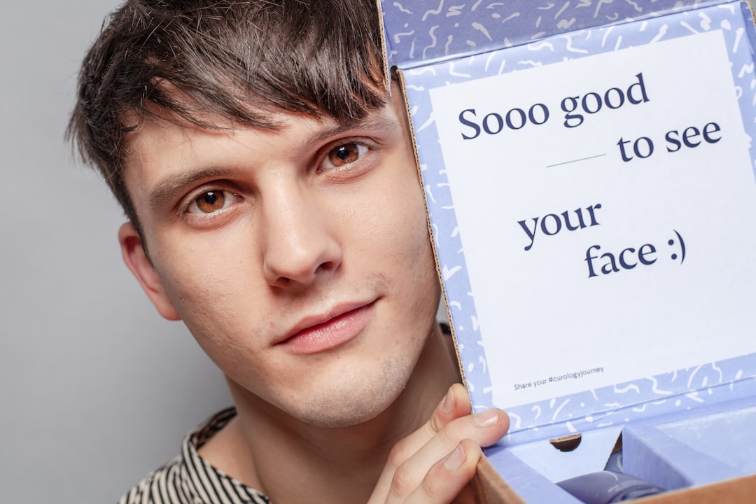 A young man holds an open box with a note inside that reads, "Sooo good to see your face :)," perfectly capturing the excitement of discovering new beauty trends.