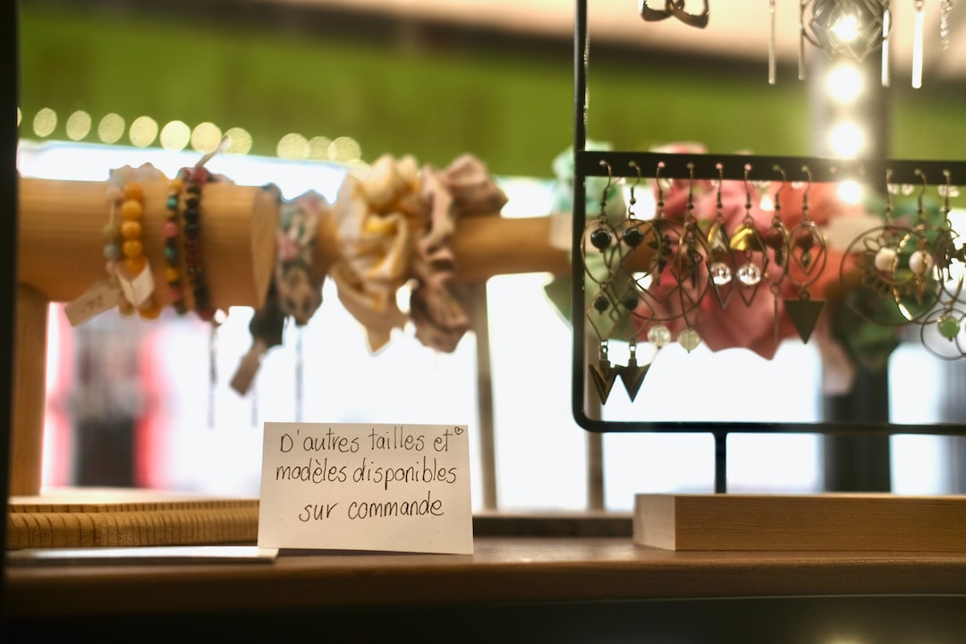 Display of colorful bracelets and chandelier earrings on stands, with a sign in French that reads, "Other sizes and models available on request." Elevate your style and shine bright with these stunning accessories.