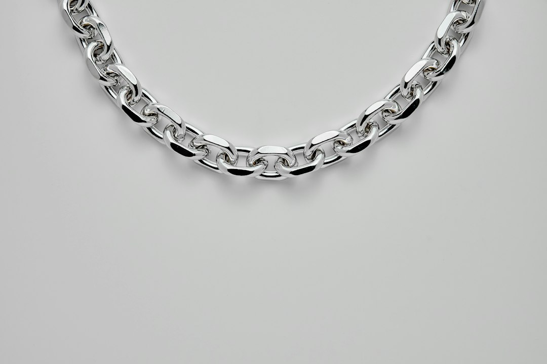 A close-up of a stunning silver chain necklace with interlocking oval links, displayed on a plain white background—perfect to elevate your style with timeless silver jewelry.