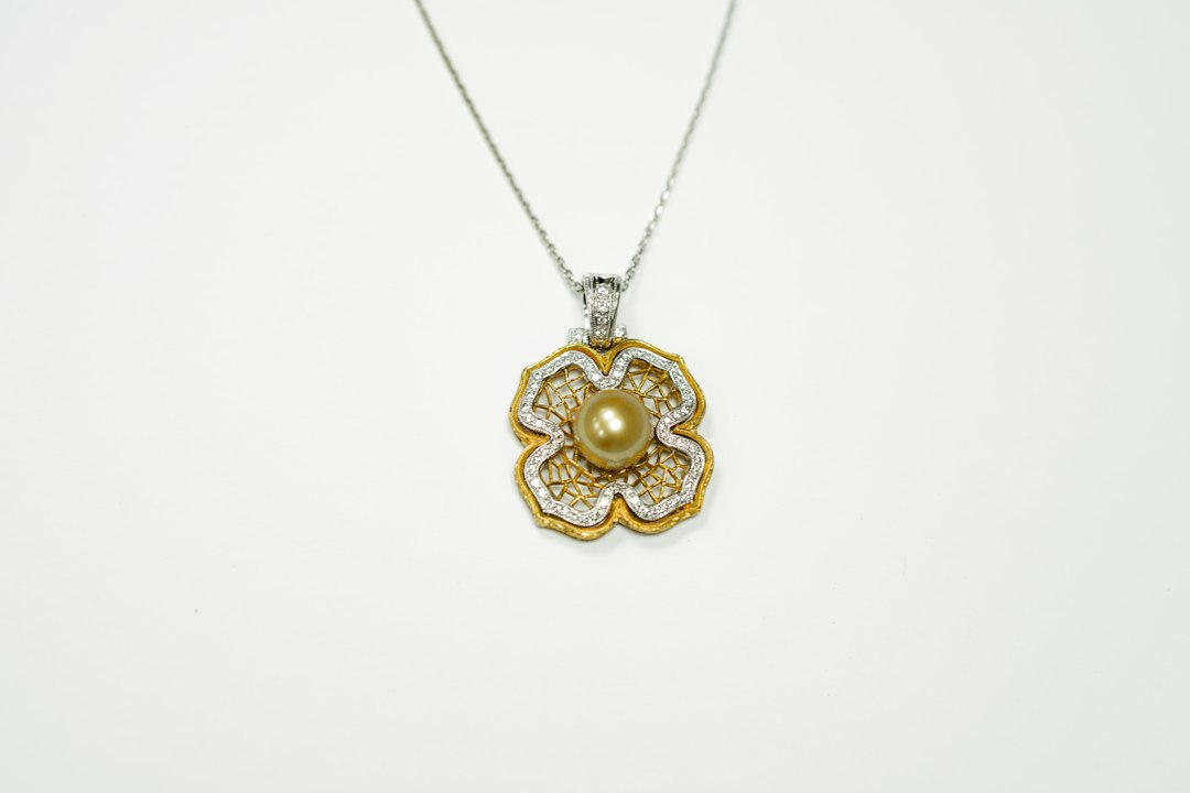 A must-have gold and silver floral pendant necklace featuring a central pearl, designed to shine like a star, displayed on a white background.