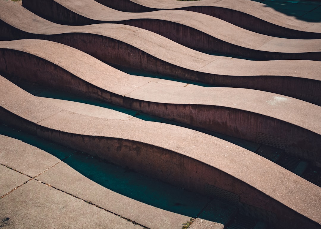 Curved concrete benches arranged in parallel rows on a paved outdoor surface, casting shadows in sunlight—an inviting spot often featured on art tours and cultural tours throughout Germany.