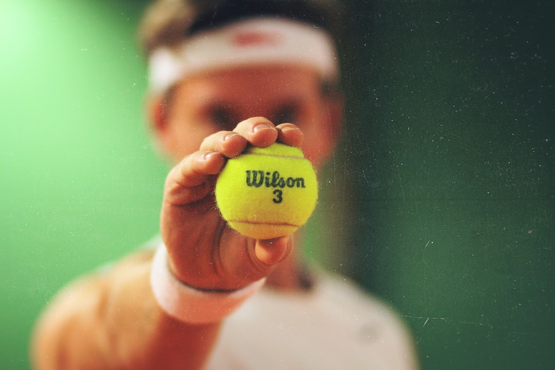 A man holding a tennis ball, ready to play on the pristine courts of an exclusive private tennis club.