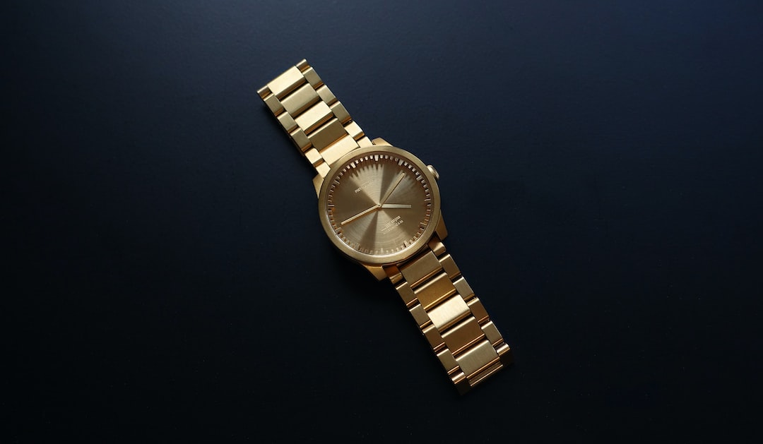 A gold Audemars Piguet wristwatch with a metal band and a plain face is displayed on a dark, solid background, echoing the timeless Legacy of the Royal Oak collection.