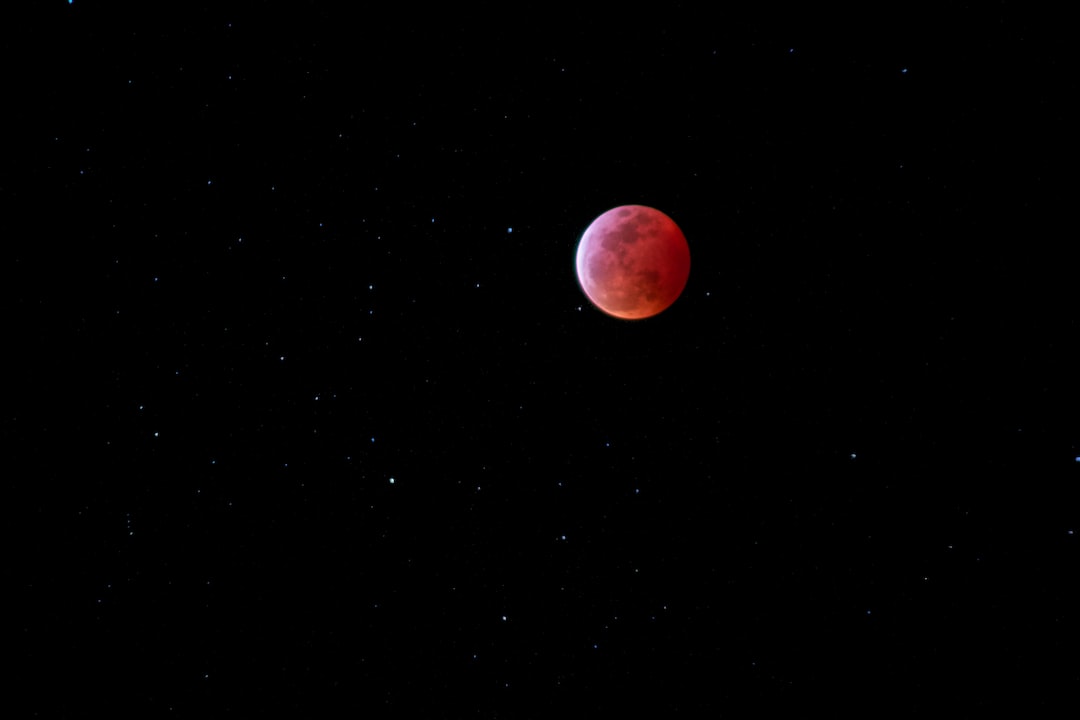 A blood-red moon is surrounded by a field of stars in a dark night sky, indicating a lunar eclipse—a breathtaking sight best viewed with high-end astronomy equipment.