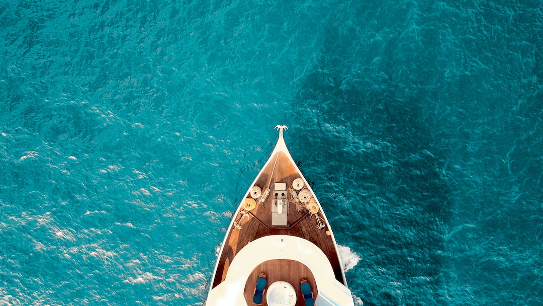 Aerial view of the bow of an elite yacht cruising through clear blue water, evoking the exclusivity once reserved for space tourism.