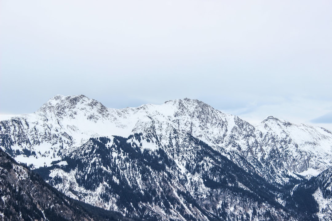 Snow-covered mountain range with rugged peaks under a cloudy sky, offering breathtaking views near exclusive private ski resorts.