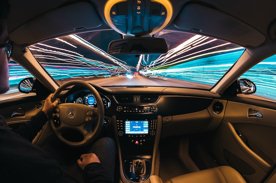 Driver inside a luxury vehicle at night with colorful light trails outside the windshield, creating a sense of speed and motion.