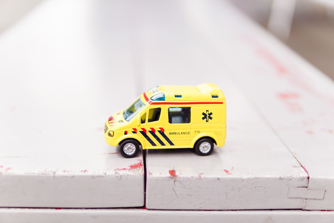 A small yellow toy ambulance sits on the edge of a white wooden surface, hinting at dreams of medical tourism and global healthcare adventures.