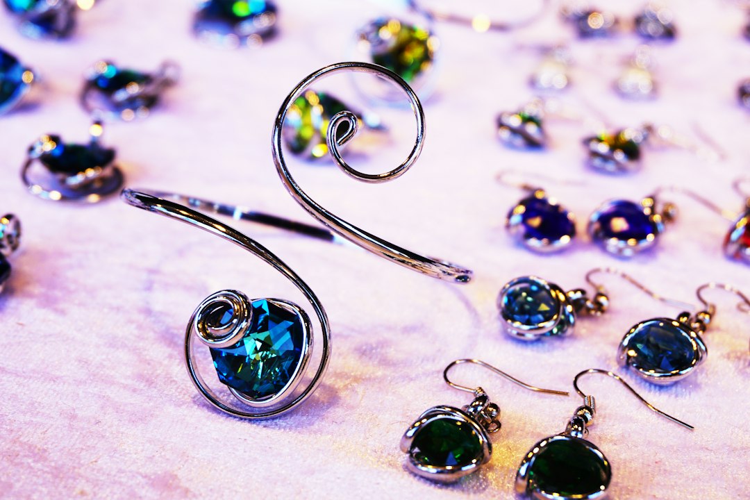 Several pieces of silver wire birthstone jewelry with blue and green gemstones are displayed on a light-colored surface, including bracelets, earrings, and pendants that exude timeless elegance.