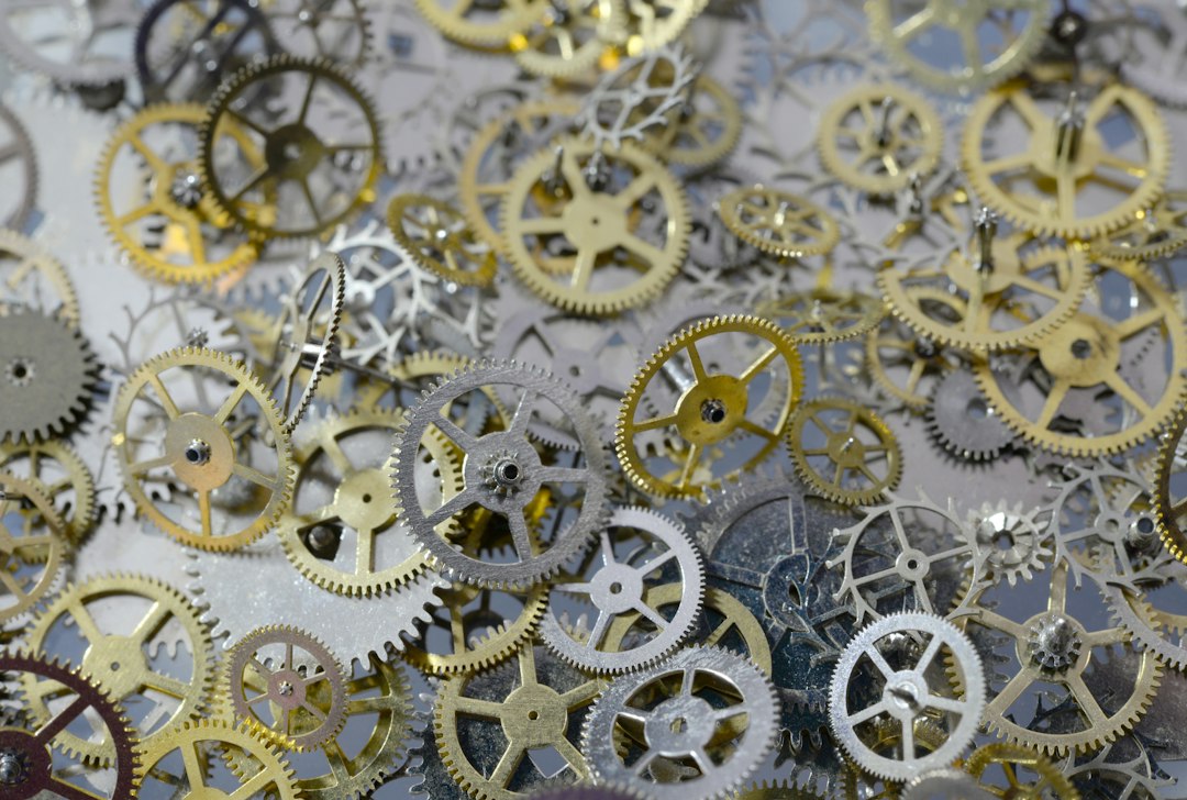 A collection of assorted brass and steel clock gears and cogs of various sizes, scattered on a flat surface—perfect for expert watch repair to keep your watch ticking smoothly.