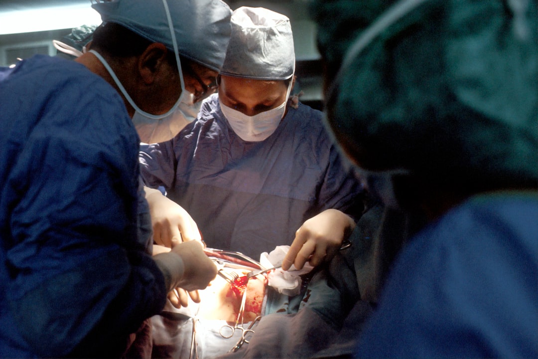 Surgeons dressed in blue scrubs and masks perform a surgical procedure on a patient in an operating room, highlighting how medical expertise can complement natural acne remedies and tips for treating acne naturally.