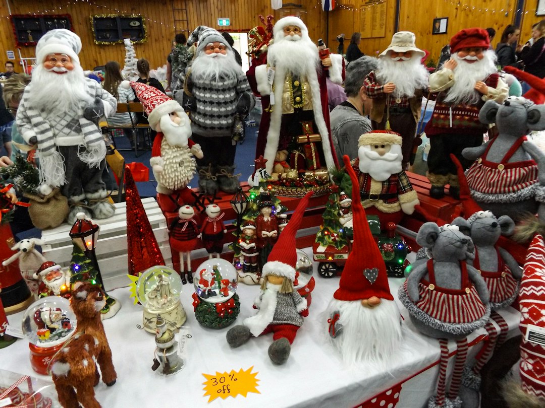 A display table with various Christmas decorations, including Santa Claus figures, vintage treasures like gnomes, snow globes, and plush animals. A "30% off" sign is visible in the foreground.