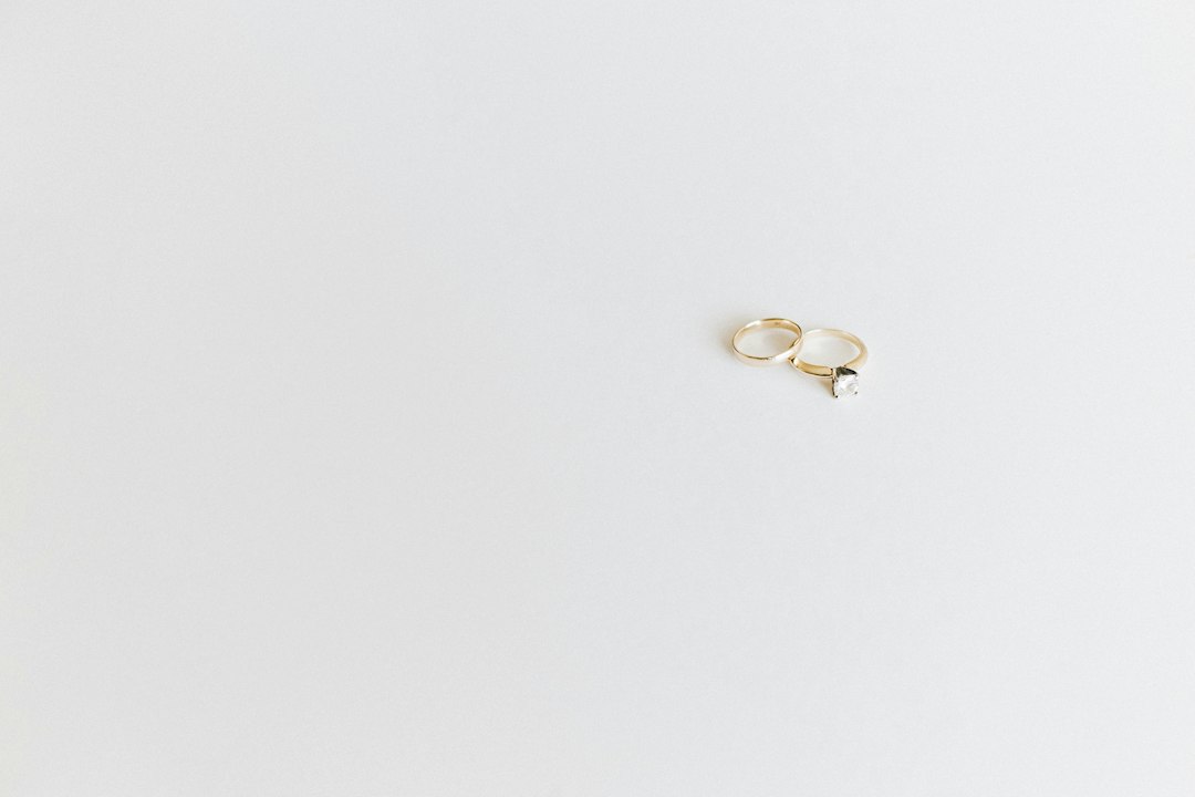 Two gold rings, one with a prominent diamond, rest on a plain white surface—showcasing the unique style and elegance of custom jewelry.