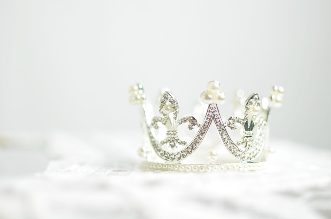 A silver jeweled crown with pearl accents, perfect for exclusive jewelry collections, resting on a white surface.