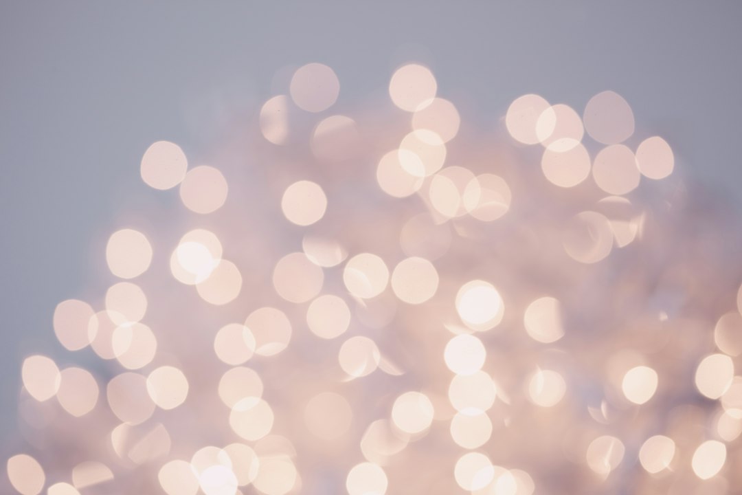 Out-of-focus white lights create a soft bokeh effect against a pale, neutral background—perfect for sharing winter skin tips or advice to combat dryness.