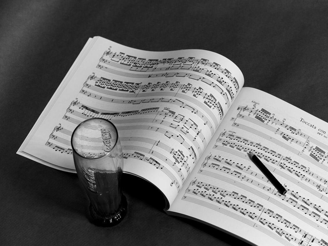 An open music score book with a pen resting on its pages and an empty glass beside it evokes the creative spirit found at exclusive festivals, where culture and music intertwine on every flat surface.