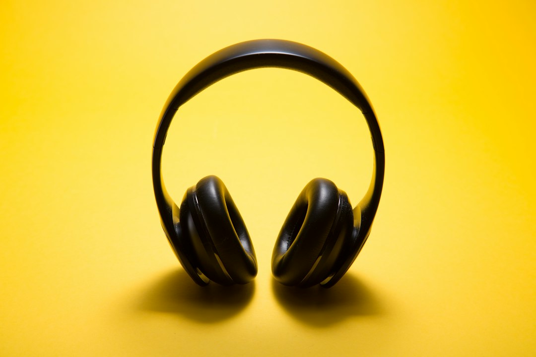 Black over-ear headphones are placed upright on a solid yellow background, echoing the modern comfort of a luxury houseboat vacation.